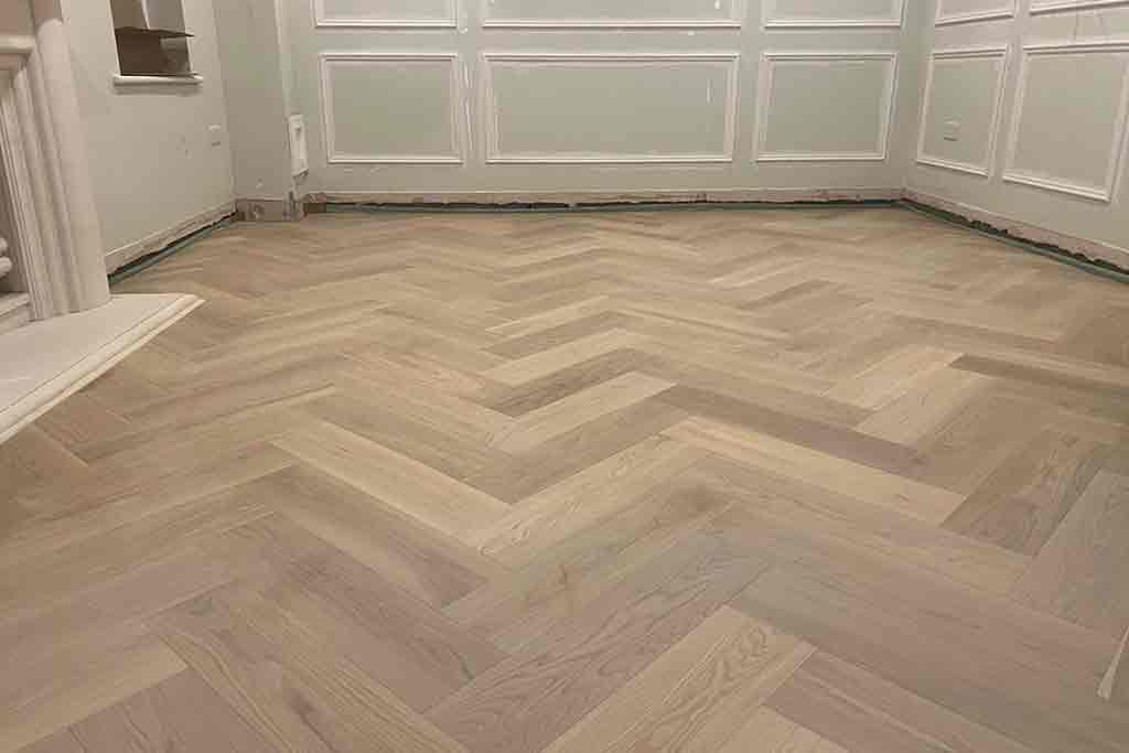 Grey oak herringbone laminate flooring fitted in a North London reception room by Carpet Masters